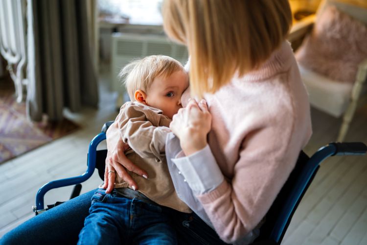 A woman sitting in a manual wheelchair cuddling a small child