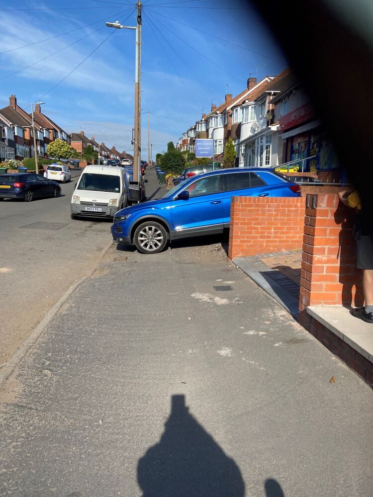 A car parked in a gully blocking the pavement.