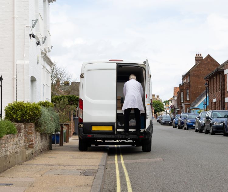 A white van parked on double yellow lines, partially blocking the pavement.