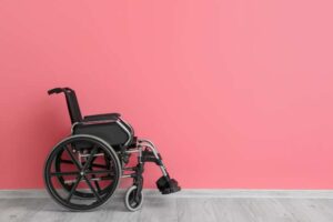 Pink background with a manual wheelchair positioned to the left