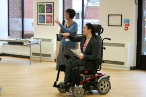 Aideen Blackborough sitting in an electric wheelchair delivering a conference speech